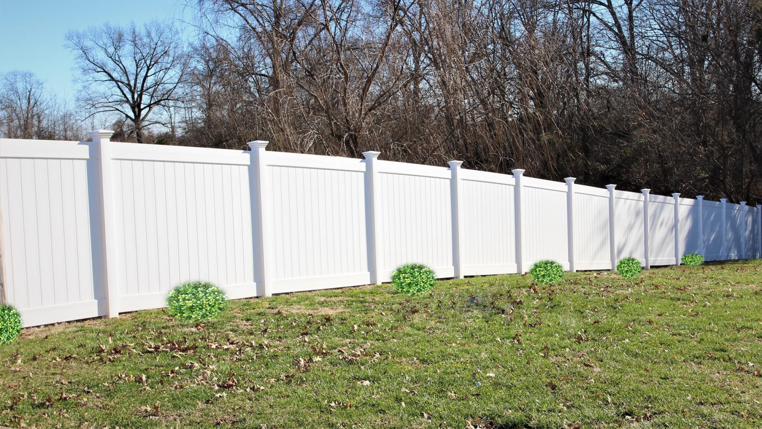 Photo of a tall, white, privacy vinyl fence in a grassy yard.